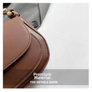 Detail of dark brown leather saddle bag with neat stitching and gold metal buckle
