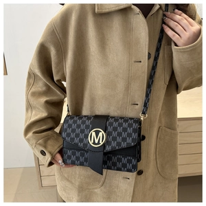 Close-up of black retro handbag with M-letter jacquard and golden round logo buckle