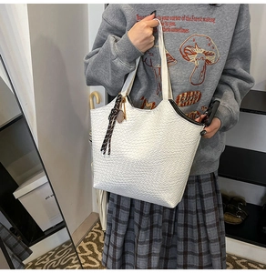 Close-up of white woven tote bag with striped silk scarf detail on female model