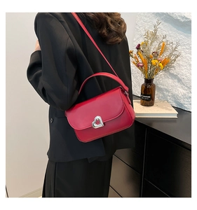 Detail of red leather saddle bag with silver heart-shaped lock and adjustable shoulder strap