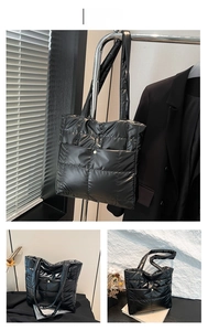 Detail of black quilted down shoulder bag with glossy nylon finish and metal round buckle
