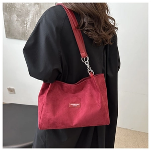 Dettaglio borsa tote in velluto bordeaux con etichetta in pelle e tracolla a catena