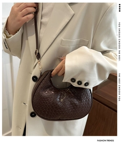Detail of dark brown woven texture on crescent bag with gold metal buckle and strap