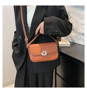 Detail of trendy caramel leather underarm bag featuring a silver heart-shaped metal twist lock