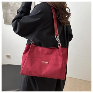 Dettaglio borsa tote bordeaux in pelle scamosciata con logo e tracolla a catena