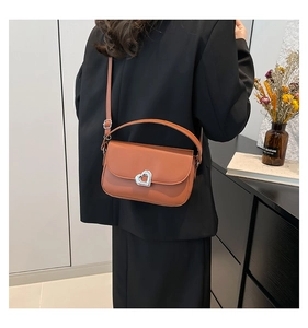 Detail of brown leather handbag with heart-shaped silver clasp and adjustable strap