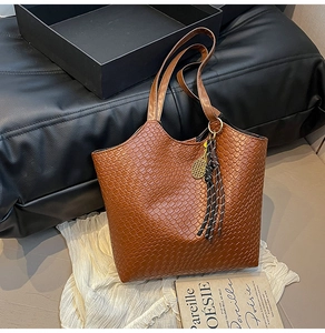 Detail of brown woven texture tote bag with golden tennis racket charm on dark background