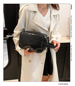 Détail de la trousse de toilette en cuir noir avec surpiqûres blanches et dragonne