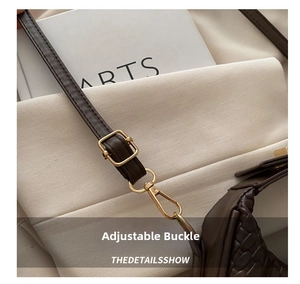 Macro detail of adjustable shoulder strap with gold hardware on woven leather crescent bag