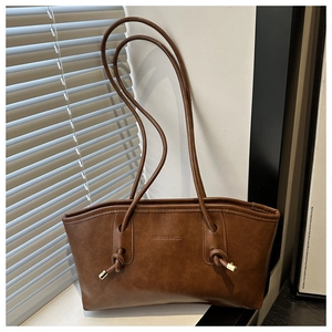Détail du sac cabas marron foncé avec bandoulières nouées et texte de mode en relief