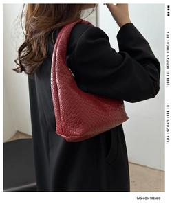 Close-up of deep red woven leather hobo bag on a black blazer with textured detail