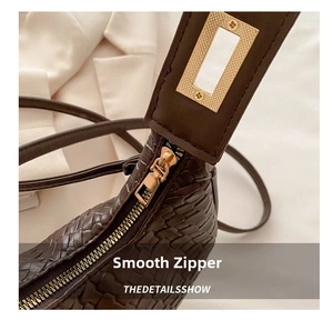Detail of brown woven texture croissant bag with smooth zipper and gold hardware