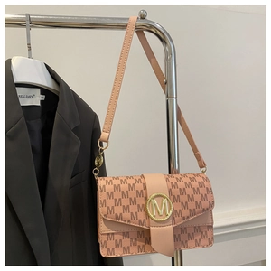 Detail of dusty pink shoulder bag with gold M-buckle and monogram pattern detail