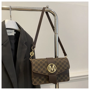 Detail of dark brown leather crossbody bag featuring gold M logo and monogram pattern