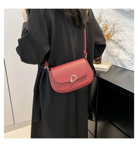 Detail of red leather saddle bag featuring a designer silver buckle on a black coat