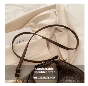 Detailed close-up of dark brown woven texture handbag with metal buckle and shoulder strap