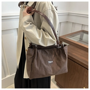 Dettaglio della borsa tote in pelle scamosciata marrone con tracolla e anello in metallo