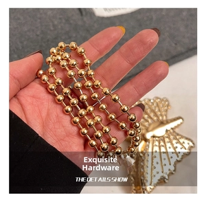 Detail shot of a polished golden bead chain with an elegant butterfly metal hardware accent