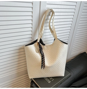 Detail of woven texture tote bag in cream white with decorative tennis racket charm