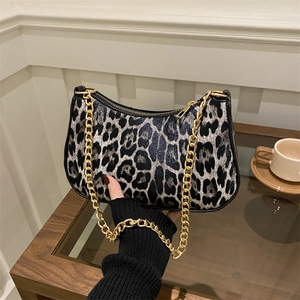 Chic leopard print hobo underarm bag with gold chain strap held in a cafe setting