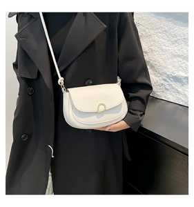 Detail of white leather saddle bag featuring an irregular gold ring buckle on the flap