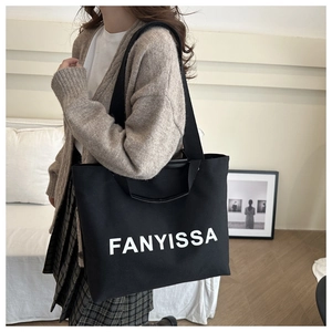 Close-up of black canvas tote bag with FANYISSA print and durable fabric strap details
