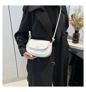 Detail of white saddle bag with unique metal ring buckle on a black trench coat