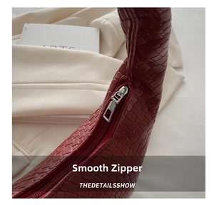 Close-up of deep red woven leather tote with smooth silver metal zipper detail