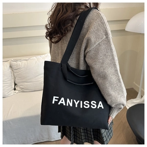 Detail of black canvas tote bag with FANYISSA lettering shown in a home setting