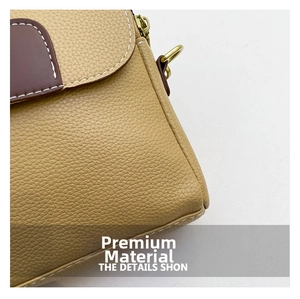Detail of khaki lychee grain leather crossbody bag with brown flap and white stitching