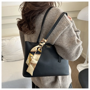 Detailed view of black leather tote bag featuring golden lettering and a floral scarf handle