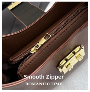 Macro shot of smooth gold metal zipper and secure side clasp on dark brown leather bag