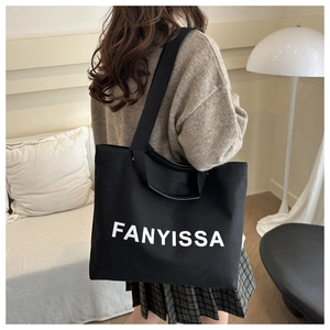 Detail of black canvas tote bag with FANYISSA lettering and dual handle strap design