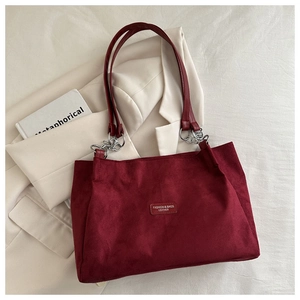 Detail of burgundy suede tote bag featuring silver chain links and long leather straps