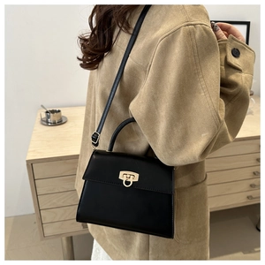 Nahaufnahme einer minimalistischen schwarzen Trapez-Tasche mit goldenem Drehverschluss