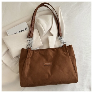Detail of brown tote bag with leather straps and silver metal chain link buckle accents