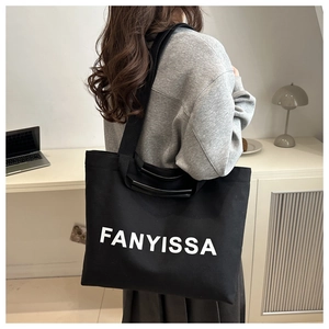 Detail of a large black canvas tote bag with white lettering for daily commuting