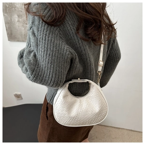 Detail of white crescent bag showing woven leather texture and gold hardware on model