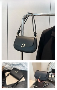 Detail of black saddle bag with irregular gold ring buckle and knotted strap accents