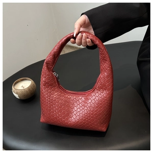 Detailed close-up of brick red woven tote bag with smooth metal zipper and leather texture