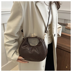 Detail of dark brown woven crescent bag showing intricate texture and golden hardware
