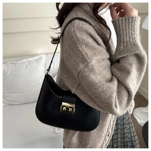 Detail of minimalist black underarm bag with gold clasp and elegant crescent design
