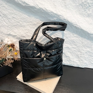 Chic black quilted puffer tote bag with gold button, displayed on a minimalist background