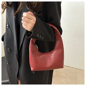 Detail of red woven leather mini hobo bag worn with a black blazer for a retro look