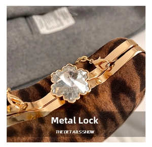Close-up of floral crystal clasp on a leopard print chain bag with gold metal accents