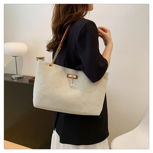 Chic cream canvas tote bag with brown leather trim and gold deer charm on shoulder
