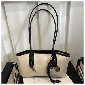 Detail of beige tote bag with black leather straps and tennis racket pendant accessory