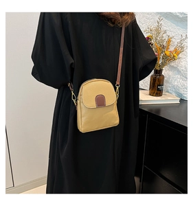 Detail of yellow pebbled leather crossbody bag with brown strap on a black dress
