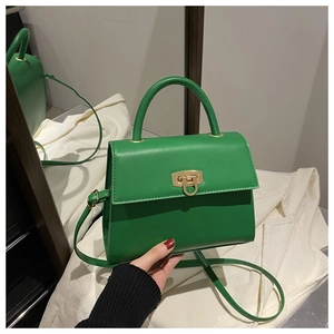 Detail einer lindgrünen Handtasche mit goldener Ringschnalle und festem Tragegriff