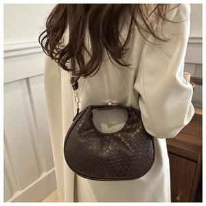 Detail of dark brown woven crescent bag with golden clasp and leather shoulder strap